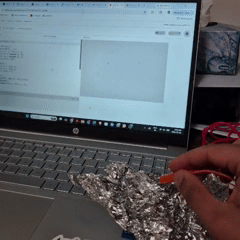 Tapping the tin foil connected to the SPACEBAR on the Makey Makey triggers small yellow explosion particles that scatter across the screen.